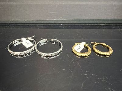 trois paires de boucles d'oreilles en anneau dorées et argentées sur un fond noir
