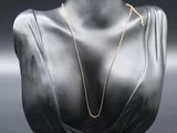 a mannequin head with a gold necklace on it