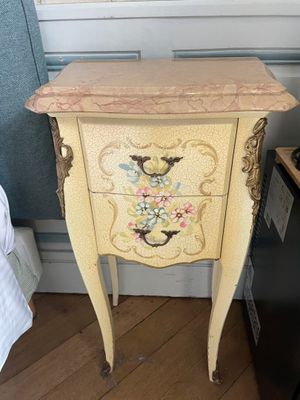 a small chest of drawers with flowers painted on it