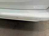 the rear end of a white car with a small dent in it