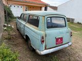 an old blue car parked in front of a house
