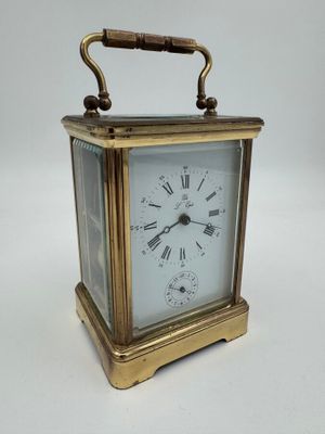 une horloge de voyage ancienne en laiton, avec des chiffres romains sur le cadran