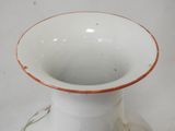 a white vase with a red rim sitting on a table