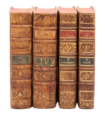 quatre vieux livres sont alignés sur une surface blanche