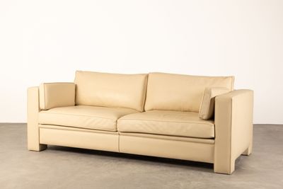 un canapé en cuir beige dans une pièce aux murs blancs