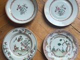 three plates with floral designs on them sitting on a wooden floor
