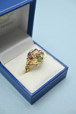 an image of a gold ring with multi colored stones in a blue box