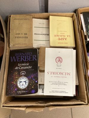 de nombreux livres dans une boîte en carton posée sur le sol