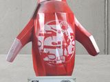 a red penguin statue on display in front of a concrete wall
