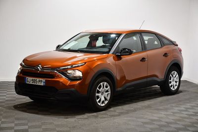 La voiture orange est garée sur un sol à damier, dans une pièce.