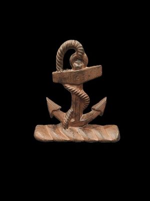 un gros plan sur une statue représentant une ancre posée sur un socle en bois