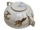 a white tea pot with a golden bird on it