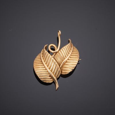 a close up of a gold leaf pendant on a black surface