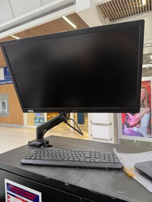 un écran d'ordinateur posé sur un bureau, avec un clavier et une souris