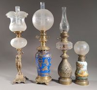 Réunion de quatre lampes à pétrole en régule ou porcelaine.