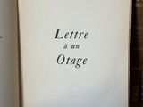 un vieux livre posé sur une table en bois, à côté d'une pile de livres