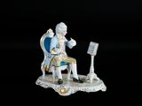 une figurine représentant un homme assis sur une chaise
