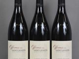Trois bouteilles de vin sont alignées sur une table en verre