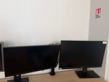 two monitors sitting on a desk next to each other