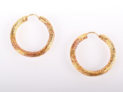 deux paires de boucles d'oreilles créoles dorées sur fond blanc