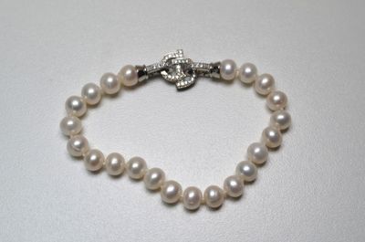un gros plan sur un bracelet de perles blanches muni d'un fermoir en argent