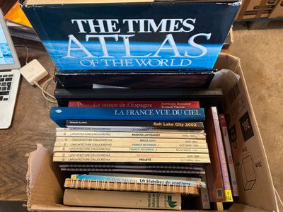 une boîte remplie de livres posée sur une table, avec un ordinateur portable à l'arrière-plan