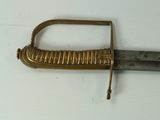 a gold colored sword with a metal handle on a white surface