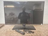 une télévision à écran plat posée sur une table, avec une télécommande