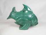a green fish statue sitting on a white surface