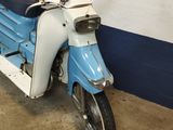 a blue and white scooter parked next to a white wall
