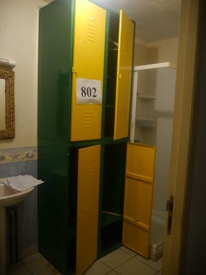 des casiers jaunes et verts dans une salle de bains équipée d'un lavabo et d'un miroir