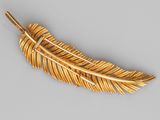 a close up of a gold feather brooch on a gray surface