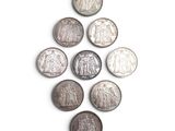 six different types of coins arranged in a triangle on a white surface