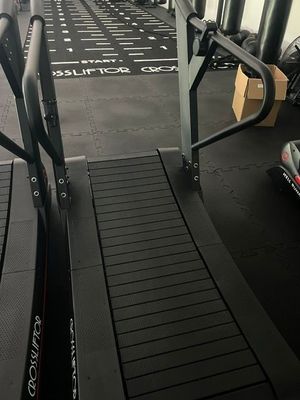 un tapis de course dans une salle de sport, à côté d'autres appareils
