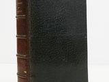 a black book with a brown cover sitting on top of a white table