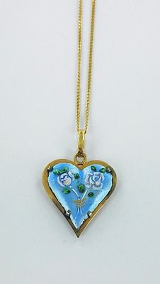 un gros plan d'un collier en forme de cœur orné de fleurs