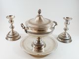 a silver plate with a bowl and two candles on it