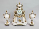 une horloge blanche et dorée et trois vases blancs