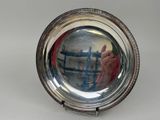 a silver plate with a reflection of a person in it