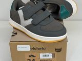 des baskets grises et vertes à velcro, avec des bandes de velcro posées sur une boîte en carton