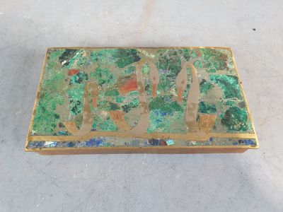 une boîte verte et dorée posée par terre