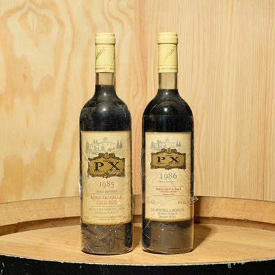 two bottles of wine sitting on top of a barrel