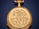 an antique gold pocket watch with a monogramed initial on the front