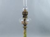 une lampe à huile ancienne avec un socle vert et un globe en verre transparent