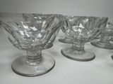 six clear glass goblets sitting on top of a white table