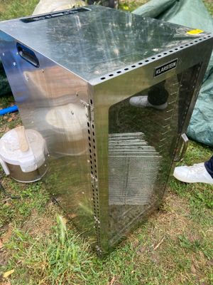 une boîte métallique posée dans l'herbe, à côté d'une poubelle