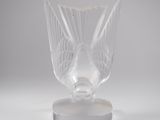 a clear glass vase on a stand on a white surface