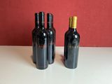 three bottles of wine sitting on a table with a red wall in the background