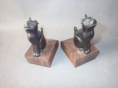two statues of cats sitting on a wooden block