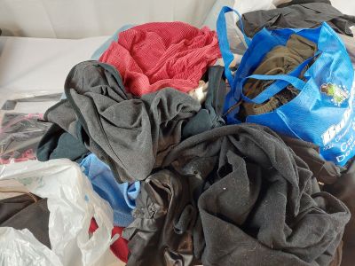 a pile of clothes on a bed with a blue bag